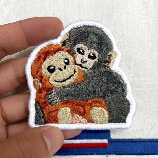 Hand Holding Cute Baby Monkeys Hugging Embroidered Patch.