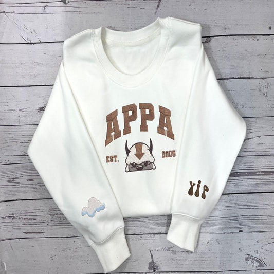White sweatshirt with embroidered Appa and sleeve icons.