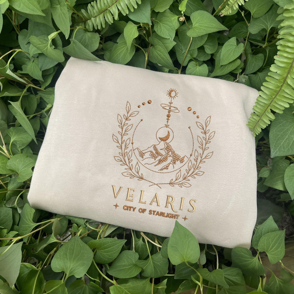 Sand Velaris moon-and-stars wreath crewneck on lush leaves