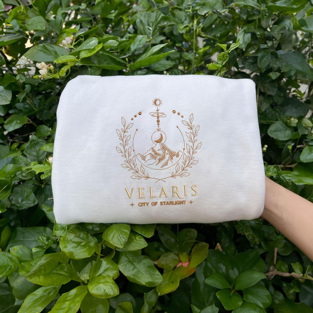 White Velaris City of Starlight gold crest held in greenery