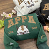 Folded green crewneck, gold “APPA 2005” embroidery