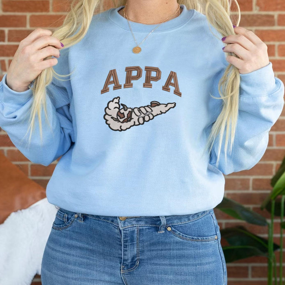 Light Blue Appa Embroidered Crewneck Against Brick Wall Styling
