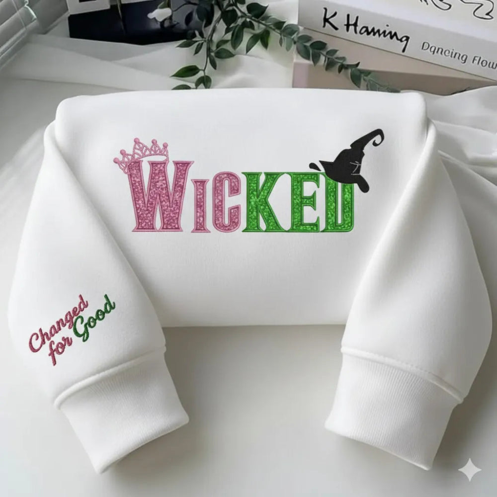 White "Wicked" Embroidered Sweatshirt Folded On Table With Books.