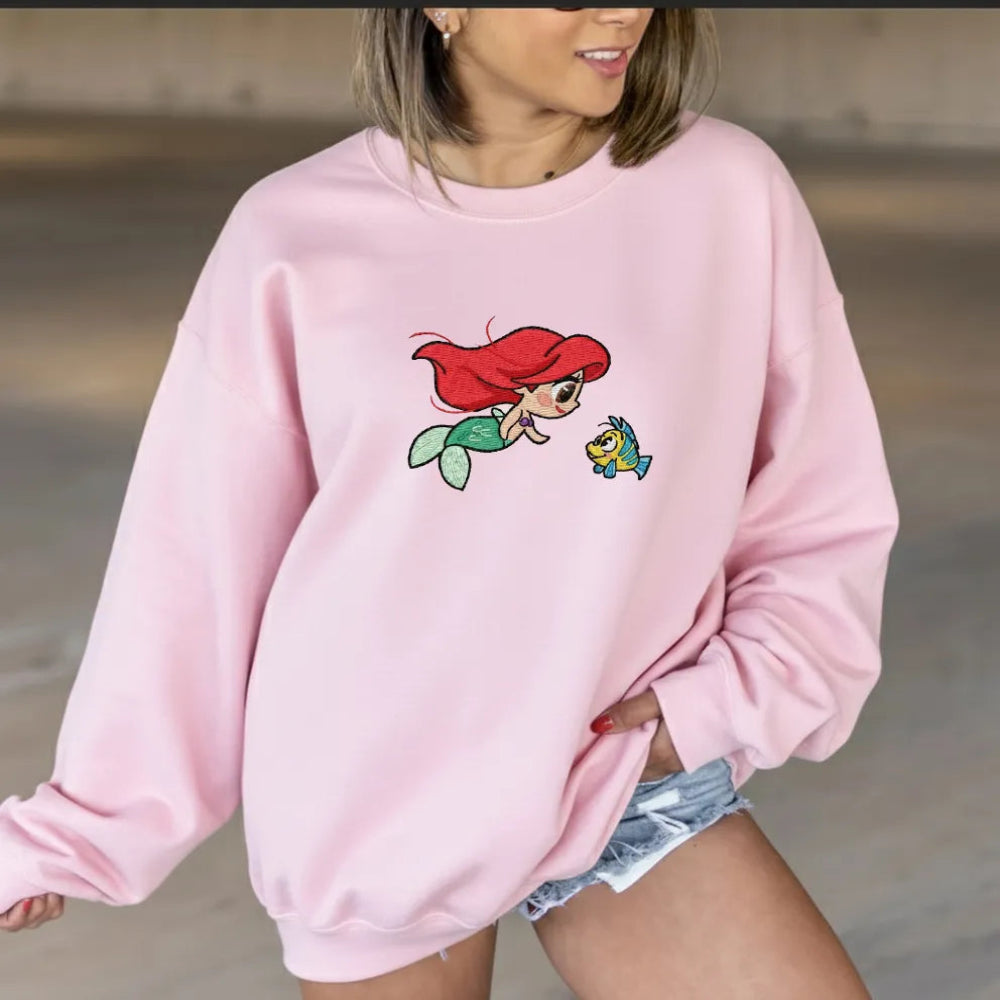 Woman In Pink Sweatshirt With Embroidered Chibi Ariel And Flounder