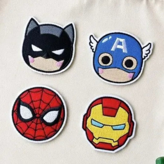 Four Chibi Superhero Faces Embroidered Patches On Beige Fabric
