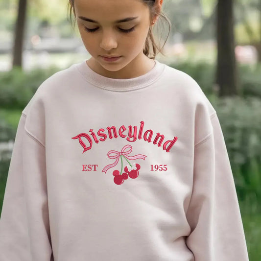 Young Girl Wearing Pink Disneyland Embroidered Sweatshirt With Cherry Design