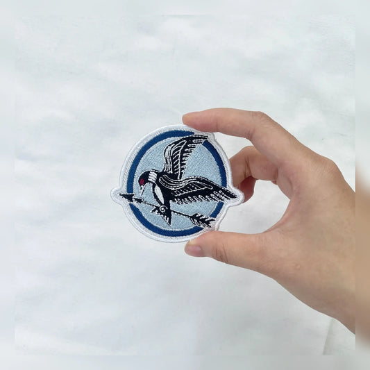 Hand Holding Mockingjay Embroidered Patch With Sharp Stitching