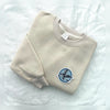 Mockingjay Embroidered Patch Displayed On Minimalist Sand Sweatshirt
