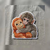 Detailed Baby Monkeys Hugging Embroidered Patch On Gray Fabric.