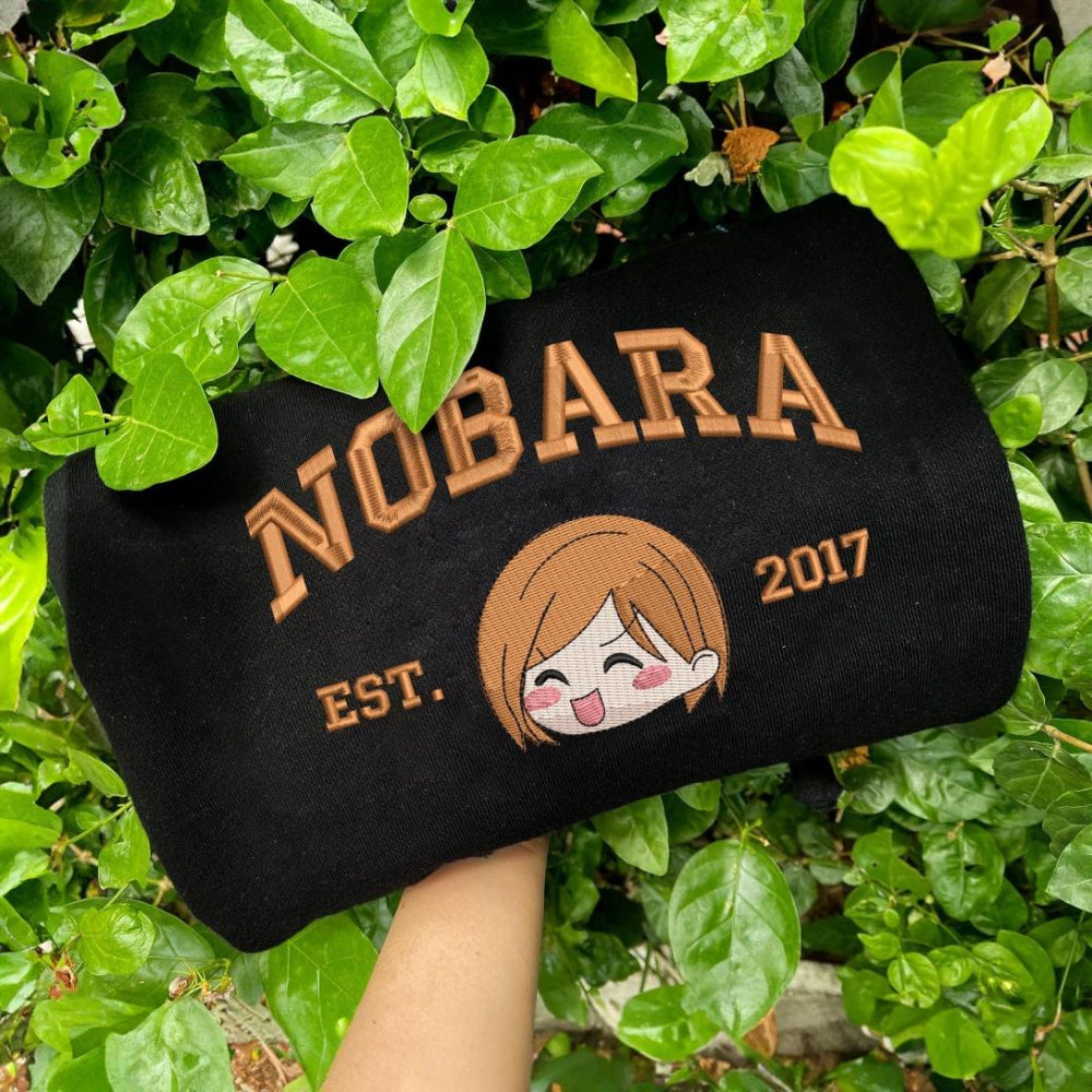 Black Nobara Est.2017 Orange Embroidery Held Among Leaves