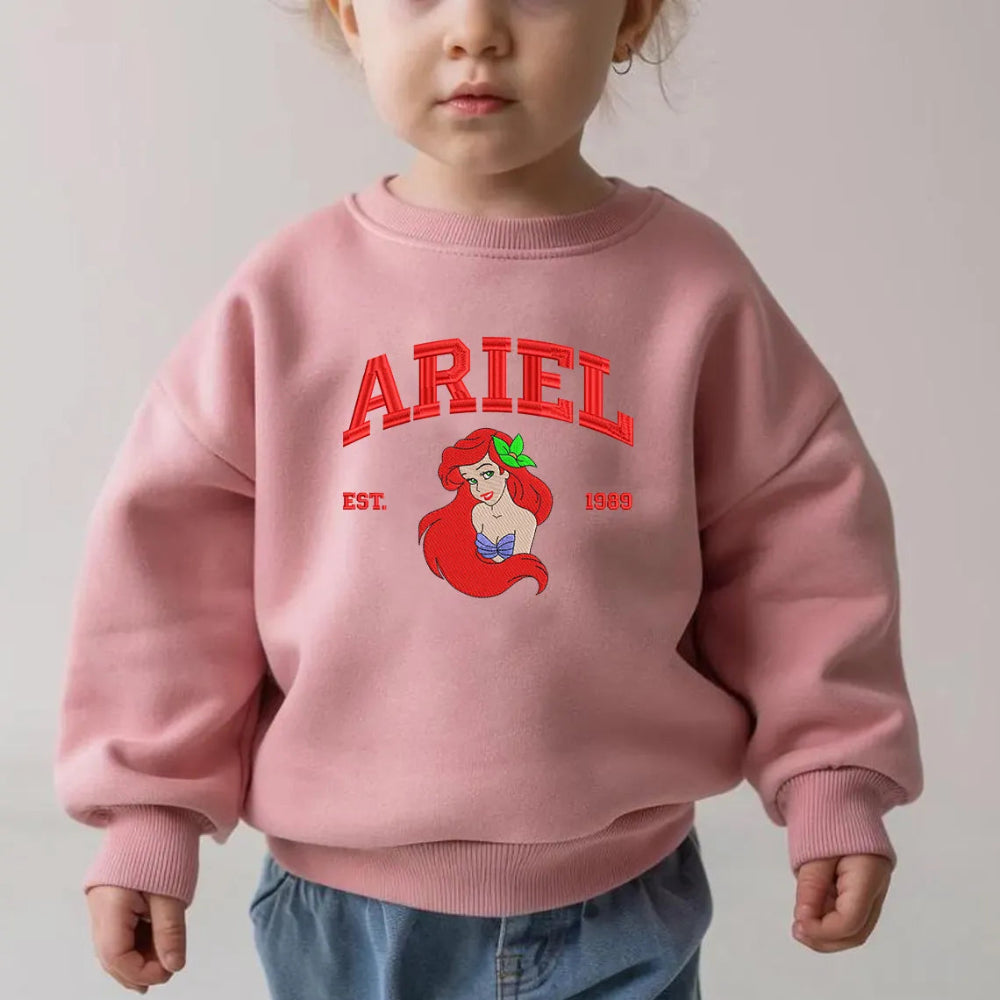 Toddler Wearing Pink Ariel Embroidered Sweatshirt With Red Varsity Text