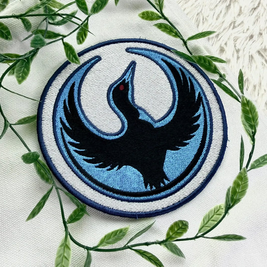 Circular Rebel Loon Patch On Fabric With Green Leaves Background
