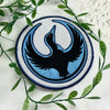 Circular Rebel Loon Patch On Fabric With Green Leaves Background
