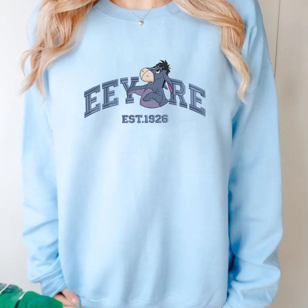 Woman Wearing Light Blue Eeyore Embroidered Sweatshirt In Casual Pose